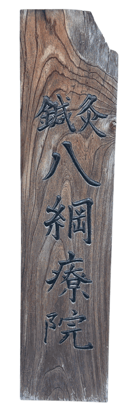 「鍼灸 八綱療院」と彫られた木の看板